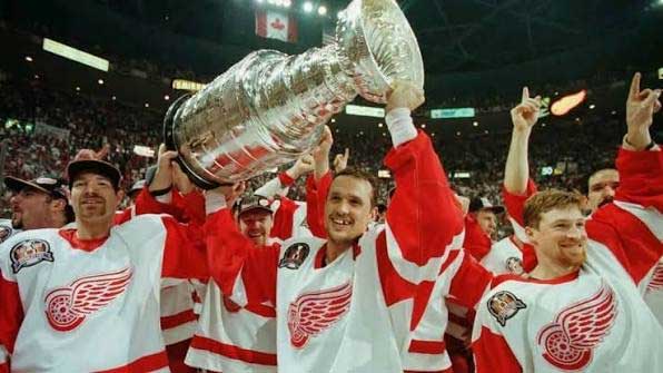 Captain Steve Yzerman holding the Stanley Cup aloft in 1997 with teammates cheering around him