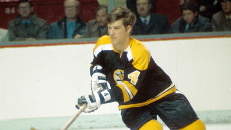 Close-up of Bobby Orr handling his wooden stick during a game, focusing on blade curve and grip