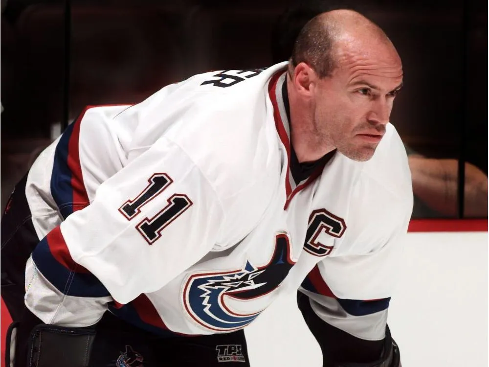Mark Messier at a press conference wearing a Rangers captain's jersey, addressing reporters